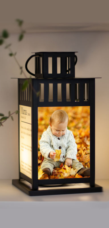 Fotolaterne schwarze m mit Baby Aufdruck im Laub
